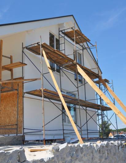 House renovation facade with wall insulation, plastering, painting walls. House remodel construction facade with scaffolding outdoors. House renovation facade with wall insulation, plastering, paiting walls. House remodel construction facade with scaffolding outdoors.